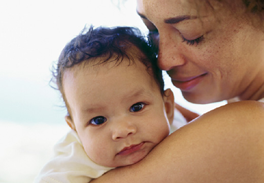 woman holding baby on her shoulder