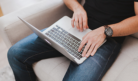 image of man sitting on couch working on laptop