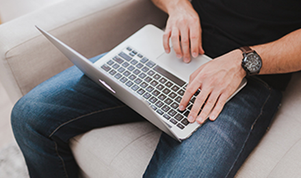 image of man typing on laptop while sitting on couch