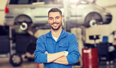 image of mechanic with vehicle suspended behind him