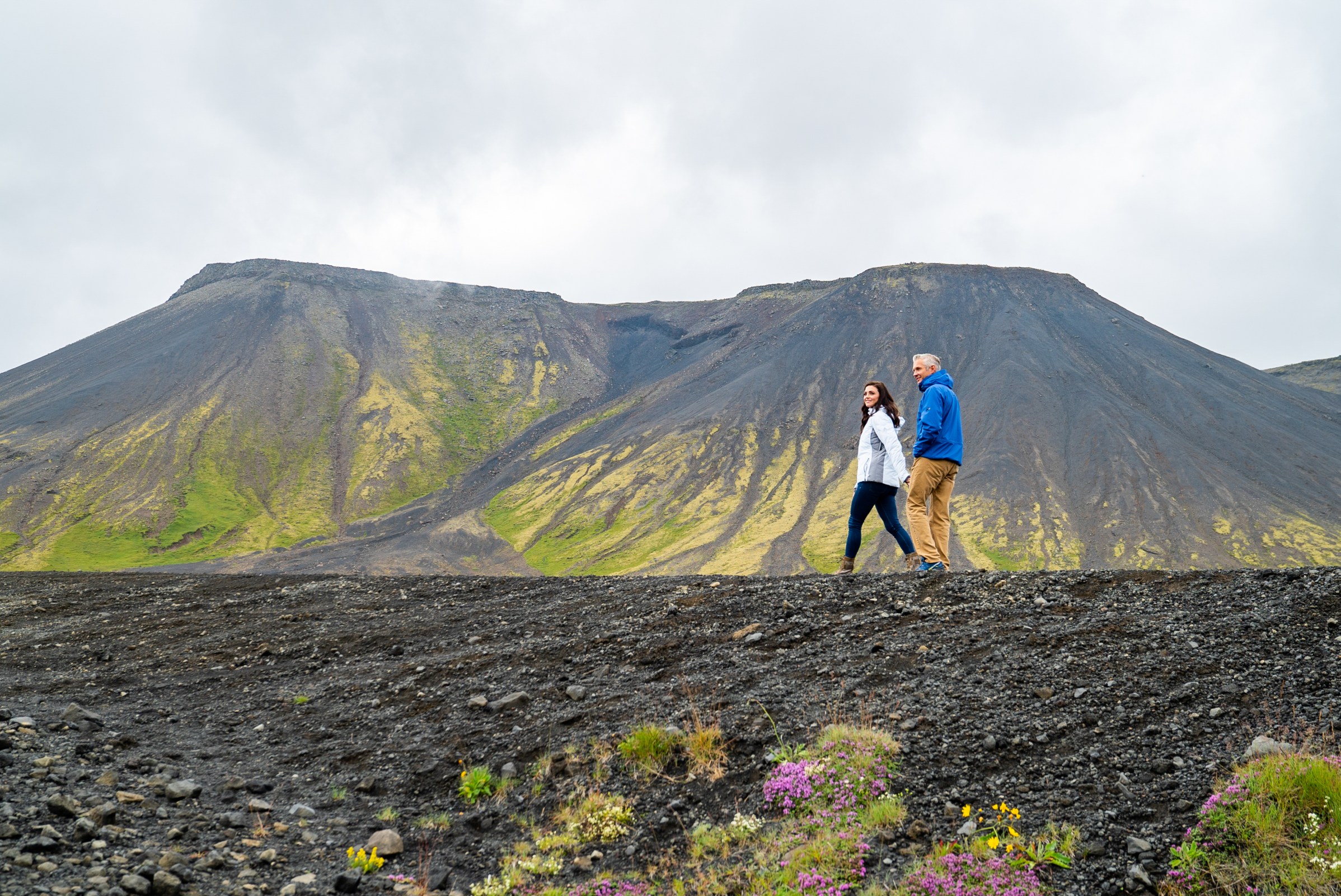 image of couple walking on a path with mountain range in the background